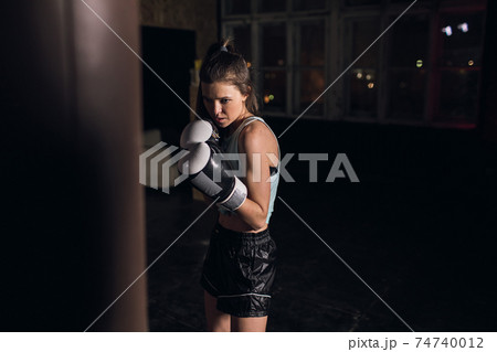 cool female fighter in boxing gloves trains in the gym. Mixed martial arts 74740012