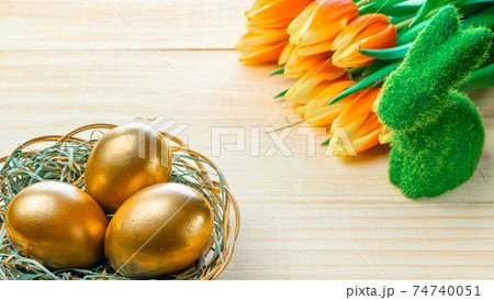 Easter eggs Golden color in basket with spring tulips, white feathers on wooden background in Happy Easter decoration. Festive decoration. Easter eggs Golden color in basket with spring tulips, white feathers on wooden background in Happy Easter decoration. Festive decoration. 74740051