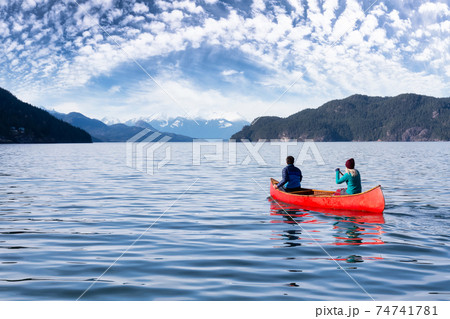Couple friends canoeing on a wooden canoe Couple friends canoeing on a wooden canoe 74741781