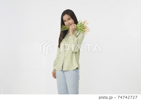 Spring Beautiful cheerful girl smiling and holding a bouquet of tulip flowers. Young happy woman. Surprise at the 8 March International Women's Day. 74742727