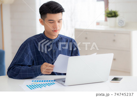 Young asian business man looking document data graph and chart paper, marketing and investment. 74745237