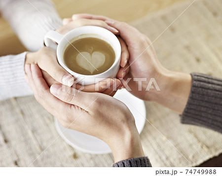 hands of young lovers holding a cup of coffee 74749988