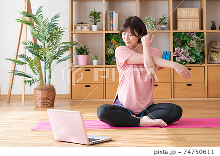 オンラインヨガ　リビングでストレッチをする若い女性 74750611