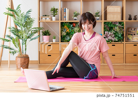 オンラインヨガ リビングでパソコンを見ながらヨガのポーズをする若い女性 オンラインヨガ リビングでパソコンを見ながらヨガのポーズをする若い女性 74751551