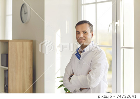 Smiling scientist or doctor in white coat standing arms crossed in laboratory or hospital Smiling scientist or doctor in white coat standing arms crossed in laboratory or hospital 74752641
