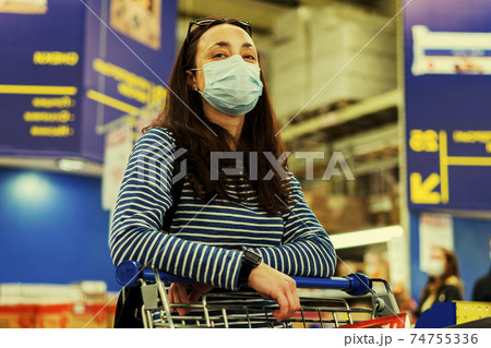 Asian young woman wearing a hygiene protective mask over her face while walking at the crowded shopping mall. Covid19 influenza in crowded place. woman wearing a mask in the supermarket. toned 74755336