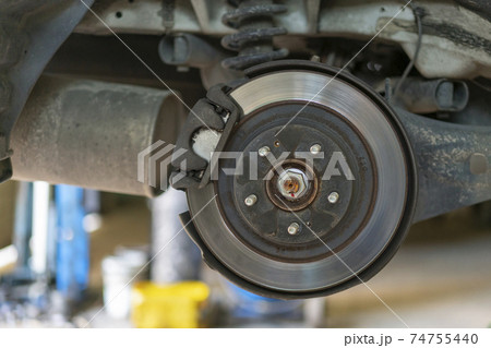 The hub of a wheel in a car service. Suspended car with no wheels. Suspension of car in service room.The car lift up by lifter for maintenance suspension and cleaning parts. Close up 74755440