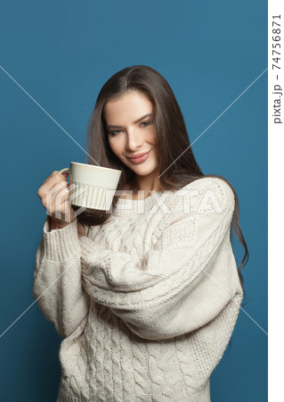 Pretty young woman drinking coffee on blue background 74756871