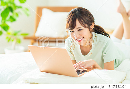 寝室でパソコンを使う若い女性 74758194