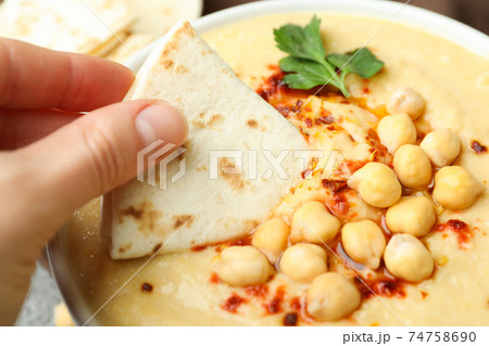 Female hand dips pita in tasty hummus, close up Female hand dips pita in tasty hummus, close up 74758690