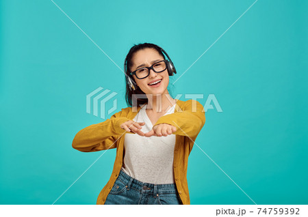 Happy young woman in headphones, blue background 74759392