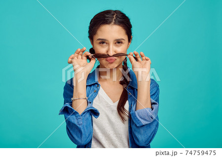 Funny young woman shows mustache, positive emotion Funny young woman shows mustache, positive emotion 74759475