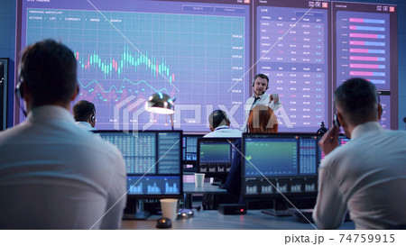 Boss speaking with stock traders in office 74759915