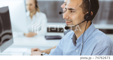 Call center. Group of casual dressed operators at work. Adult businessman in headset at customer service office. Telesales in business 74762673