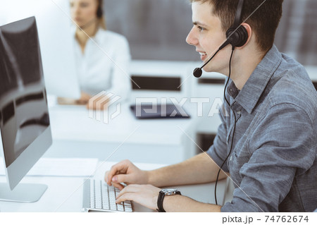 Call center. Group of casual dressed operators at work. Businessman in headset at customer service office. Telesales in business 74762674