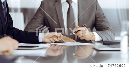 Unknown business people working together at meeting in modern office, close-up. Businessman and woman with colleagues or lawyers discussing contract at negotiation 74762692