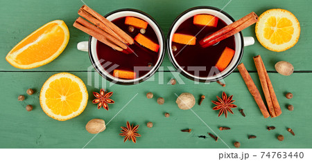Mulled red wine with spices and fruits on a wooden table. Wide photo. 74763440