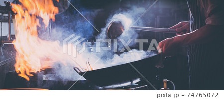 Chef stir fry busy cooking in kitchen Chef stir fry busy cooking in kitchen 74765072