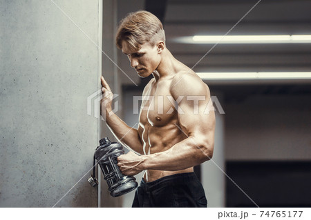 Bodybuilder drinking water after fitness workout 74765177