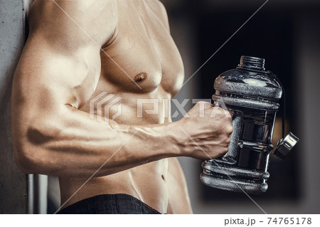 Bodybuilder drinking water after fitness workout 74765178