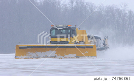 Snowy winter at the airport - a big snowplow removes snow from the path on the way Snowy winter at the airport - a big snowplow removes snow from the path on the way 74766862