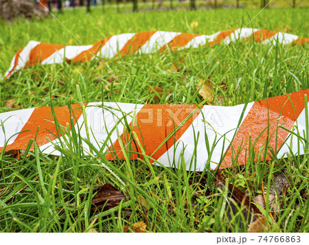 Boundary striped ribbon on green grass. 74766863