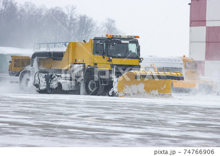 Snowy winter at the airport and snowplow removes snow from the runway 74766906