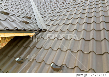Close up of new house roof structure covered with metal tile sheets. Close up of new house roof structure covered with metal tile sheets. 74767643