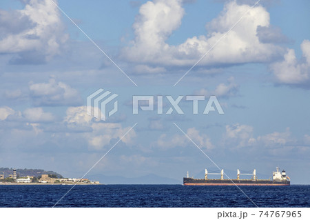 cargo ship nearby Capo Peloro Lighthouse in Punta del Faro on the Strait of Messina, most north eastern promontory of Sicily, Italy cargo ship nearby Capo Peloro Lighthouse in Punta del Faro on the Strait of Messina, most north eastern promontory of Sicily, Italy 74767965