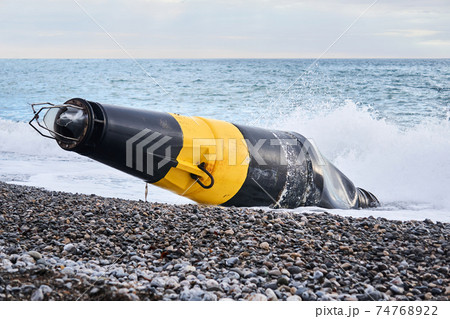 damaged sea buoy (cardinal danger mark) washed ashore after a storm 74768922