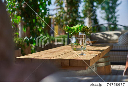Cozy terrace with sofas for rest, Glass with champagne on a wooden table. Cozy terrace with sofas for rest, Glass with champagne on a wooden table. 74768977