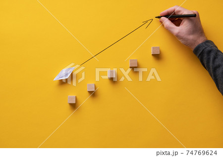 Drawing an arrow pointing upwards in front of an origami made paper boat 74769624