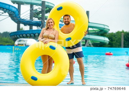 a man and a woman in a rubber inflatable circle stand against the background of a summer water park pool a man and a woman in a rubber inflatable circle stand against the background of a summer water park pool 74769646