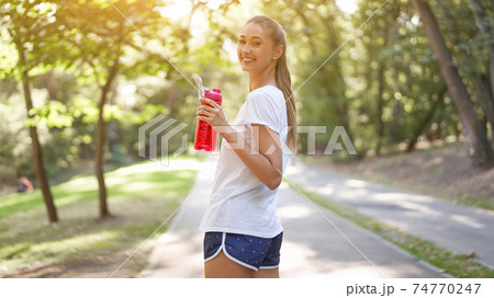 Woman drink water red bottle after morning workout. Woman drink water red bottle after morning workout. 74770247
