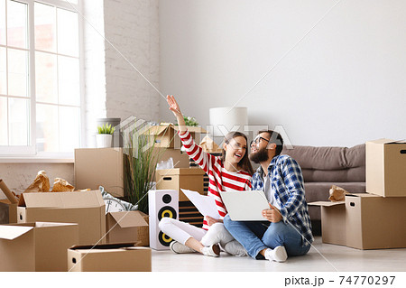 Content couple with laptop planning design of new apartment 74770297