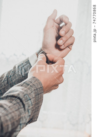 Groom's morning, details and husband's meeting on the wedding day. Man adjusts a watch on his hand on a white background. 74770868