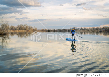 Paddling stand up paddleboard on a calm lake 74771622