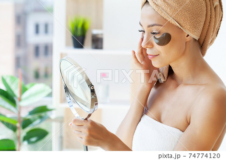 Young woman with beautiful skin puts black patches on her face 74774120