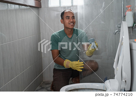 a man wearing gloves cleaned the toilet glass divider a man wearing gloves cleaned the toilet glass divider 74774210