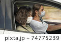 Young couple wearing protective face mask are sitting in the car. Corona virus pandemic concept.Road trip in new normality. 74775239