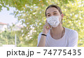 Young happy man with face mask talking on the phone outside. New normal after coronavirus outbreak. Healthy lifestyles and technology concepts. 74775435
