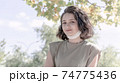 Portrait of young charming woman in medical mask. Her face mask is under the chin. New normality after covid-19 pandemic. 74775436
