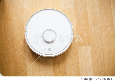 Smart House. Vacuum cleaner robot runs on wood floor in a office 74776303