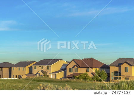 Exterior of houses with gable and valley and hip roof designs against blue sky Exterior of houses with gable and valley and hip roof designs against blue sky 74777157