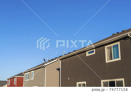 Houses with close up view of exterior walls windows and roofs against blue sky Houses with close up view of exterior walls windows and roofs against blue sky 74777158