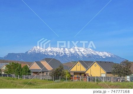 Single storey houses against striking snow capped mountain and vibrant blue sky Single storey houses against striking snow capped mountain and vibrant blue sky 74777168
