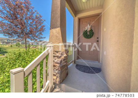 Festive home entrance with stairs leading to front door decorated with wreath Festive home entrance with stairs leading to front door decorated with wreath 74778503