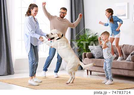 Cheerful family with kids and dog dancing at home 74783714