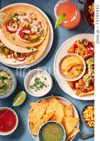 Mexican food on a blue background. Nachos, tacos, dips, cocktails Mexican food on a blue background. Nachos, tacos, dips, cocktails 74785931