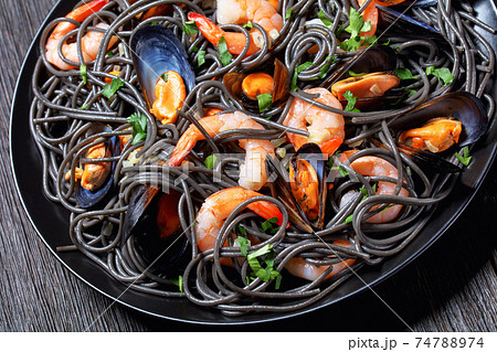Squid ink pasta with mussels and shrimps, top view 74788974